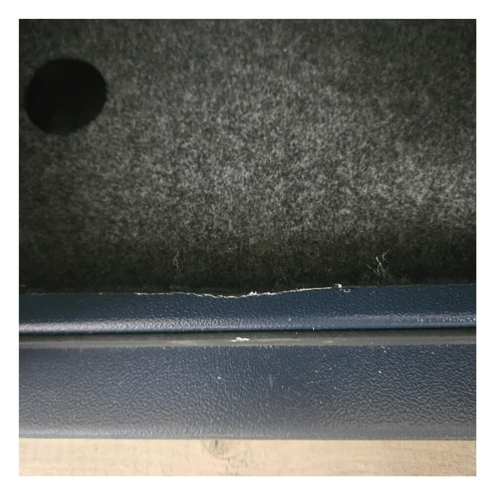 Close-up of a carpeted surface with a blue metal strip at the bottom