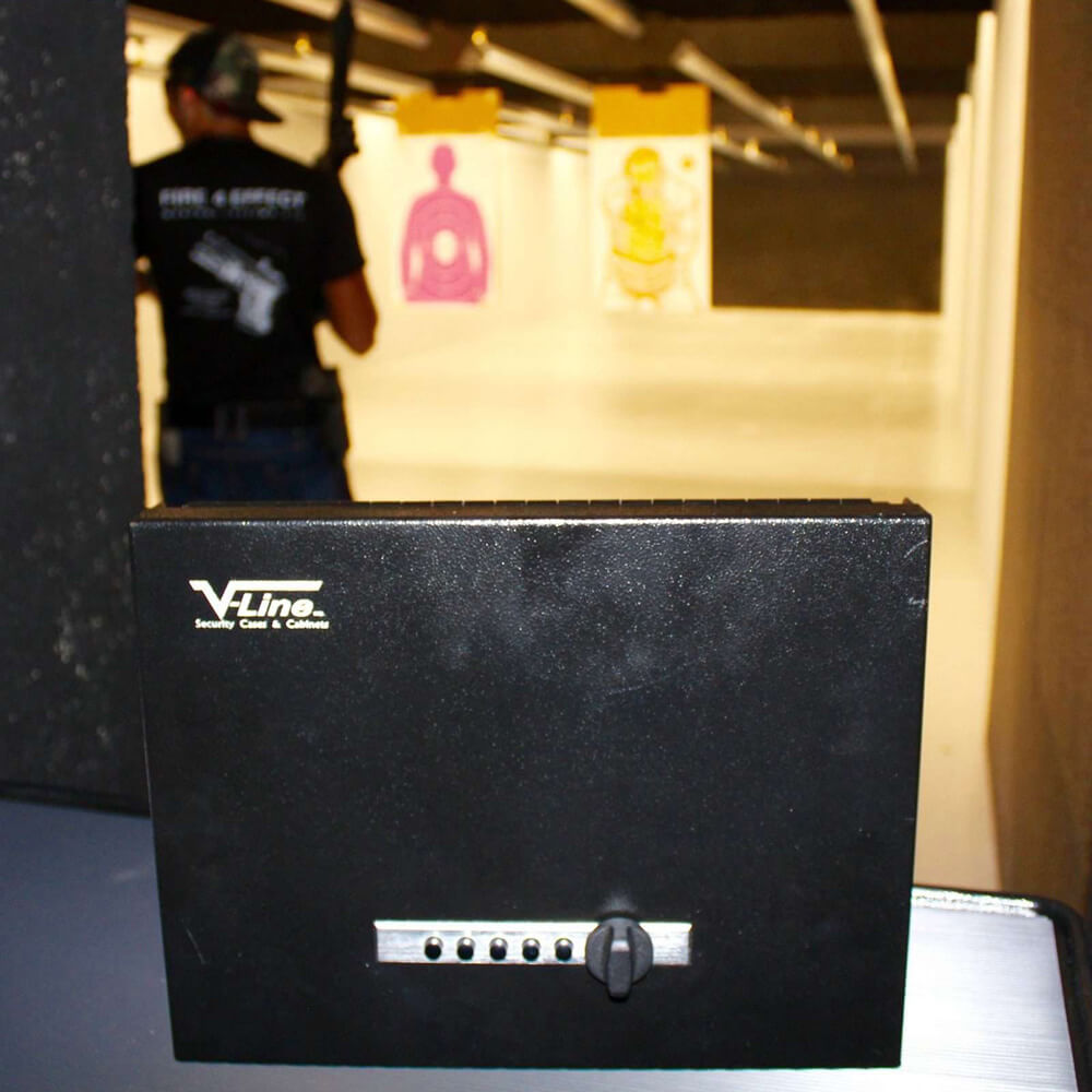 V-Line Top Draw XD handgun safe with heavy-duty lock cover, shown on a target-range background for secure firearm storage.